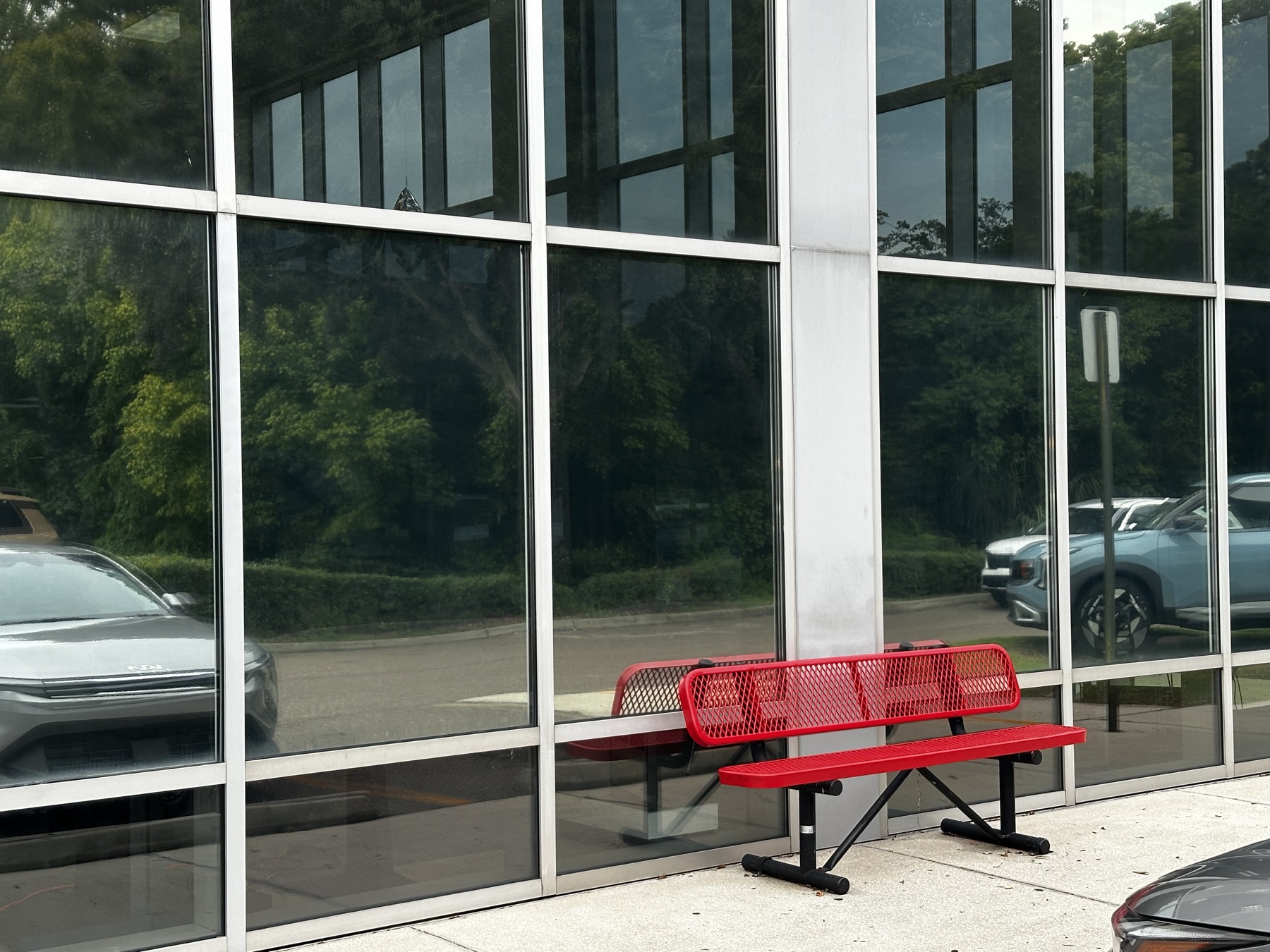 Exterior storefront glass with tint reflecting trees and vehicles